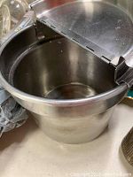 Top view inside the stainless steel warming pot showing the interior and the hinged lid partially open.