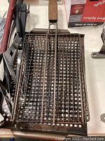 Top and side view of wire BBQ grill basket with wooden handle showing its structure and size