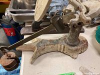 Side view of antique cast metal scale showing base, lever arm, and worn paint with rust.