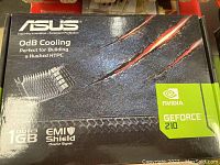 Box of ASUS NVIDIA GeForce 210 featuring 1GB DDR3 memory, EMI shield, and 0dB cooling suitable for silent PC builds.