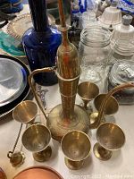Overview of the Turkish copper ewer alongside six matching copper cups, showing ornate engraved details and patina.
