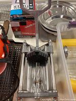 View of fry cutter showing metal pressing handle, rods, and black plastic cutting grid.