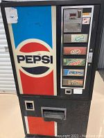 Front view of the vending machine showing Pepsi branding, coin slot, and drink selection buttons with brands Sprite Zero, Dr Pepper, Mountain Dew, Pepsi, and Fanta.