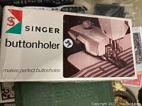 Original box with Singer branding and image of buttonholer attachment on a sewing machine.