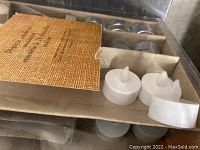Open box showing white battery-operated LED tea light candles with plastic flame tips and larger wax tea lights.