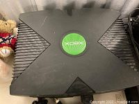 Top view of black Xbox console with green logo on top showing light surface scratches.