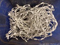 Photo showing a tangled string of white icicle Christmas lights with multiple small white bulb sockets laid inside a blue container.