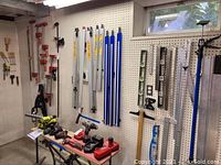 Wide view of pegboard wall showing various clamps, levels, rulers, chisels, work belt and Quick-Grip clamp