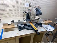 Front view of saw mounted on workbench showing sliding rails, base and blade guard