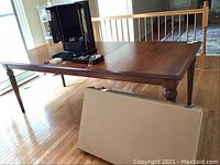 Full view of dining table and cardboard box containing extension leaf