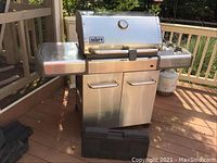 Front view of stainless steel grill with side shelves and cabinet