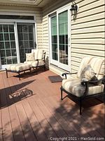 Wide shot of two lounge chairs, ottoman and side table on deck in front of sliding door