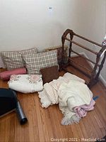 View of assorted pillows and quilts on floor beside the wooden quilt rack.
