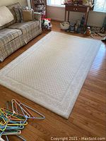 Full view of the area rug on hardwood floor alongside a couch and various household items.