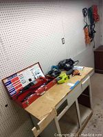 Wide view of tools and extension cords on pegboard and workbench, showing metal case, saws, nailer and cords.