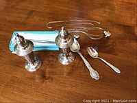 Photo showing all items including salt and pepper shakers, spoons, chains, pendant, earrings, and pen in case arranged on wooden surface.