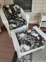 Wicker chair with floral cushion alongside matching ottoman, showing full view of the set.