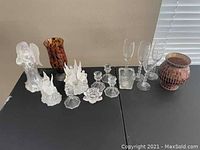 Wide view of collection showing frosted elephant and bird figurines, candle holders, flower shape, champagne flutes, and mosaic vase.