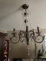 Glass bead chandelier hanging from ceiling with multiple curved arms and glass bead strands.