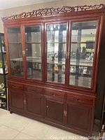 Front view of large rosewood curio cabinet showing glass upper doors, drawers and lower storage cabinets.
