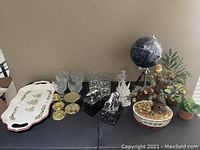 Full lot overview showing all items including money tree, globe, plants, marble figures, glassware, gold candle holders, and porcelain tray