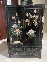 Full view of the Oriental storage chest with floral and bird artwork on black lacquered wood.