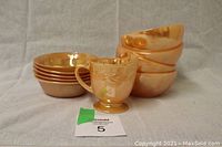 Front view of the creamer, 4 medium bowls, and 5 smaller bowls arranged to show size and finish