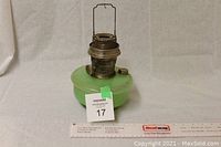 Front view of complete oil lamp showing green glass base and brass burner with lot tag
