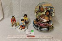 The full lot includes three Native American figurines and eight painted Native American-themed plates stacked showing the front of the top plate.