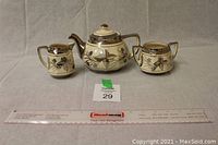 Full set of Price Bros ceramic teapot, creamer, and sugar bowl with silver trim and black floral design shown with measurement ruler for scale.