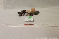 19 assorted unique rocks arrayed on white fabric background with measuring ruler and lot number card for scale
