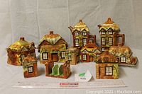 Full lot of 10 ceramic cottage items arranged on cloth background with measuring ruler in front