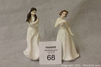 Photo showing both Royal Doulton dolls side by side, displaying their full height, white dresses, and facial features.