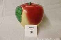 Front and side view of red ceramic apple cookie jar with small stem on lid and green leaves on the body.