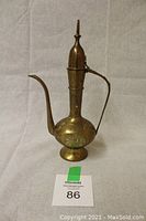 Full view of the vintage brass teapot showing its overall shape and handle.