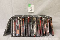 Photo showing a row of 25 assorted thriller and action movie DVDs in cases, stacked upright horizontally with one leaning vertically on each end.