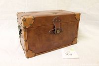 Brown vintage style trunk closed, showing leather look surface with metal corner rivets and front clasp lock