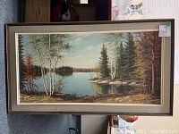 Full view of the framed landscape oil painting showing the lakeside scene with birch and pine trees.