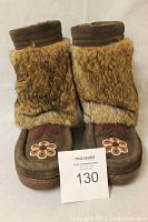 Front view of pair of women's mukluks in brown suede with fur upper and beaded floral design on toes.