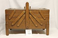 Front view of vintage wooden sewing trunk with folding arm compartments closed.