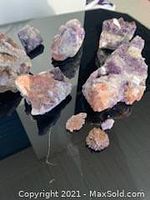 Photo showing multiple quartz rocks on a black surface with varying colors purple and orange.