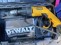 Wide view of DeWalt hammer drill in case with manual and drill bit