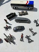 Group of mixed diecast and plastic toy vehicles and figures on white surface with shadows