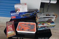 Overall view of the assorted tools with various boxed power tools, hand tools in orange case, and sanding blocks