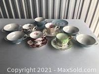 Collection of 6 tea cups and matching saucers with various floral and solid colors including red floral, light green, and white.
