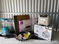 Group shot of appliances and cookware, includes blender, toaster oven, rice cooker, frying pans, and hotplate in packaging