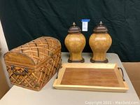Full lot view showing decorative woven trunk, wooden tray, and two covered vases with lids.