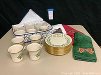 Full set showing 10 plates stacked, 8 mugs arranged, and 3 holiday hand towels folded