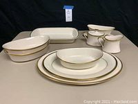 Full view of Lenox Eternal serving pieces set displayed on table showing platters, casserole dish, bowls, gravy boat, and cream and sugar set.