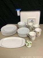 Set of white dishes including dinner plates, bowls, salad plates, Lenox floral mugs, a white oval serving tray, and Royal Albert ceramic flowers with a floral picture frame.